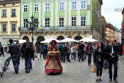 Дівчина з квітами в оточенні відвідувачів площі Ринок у Львові